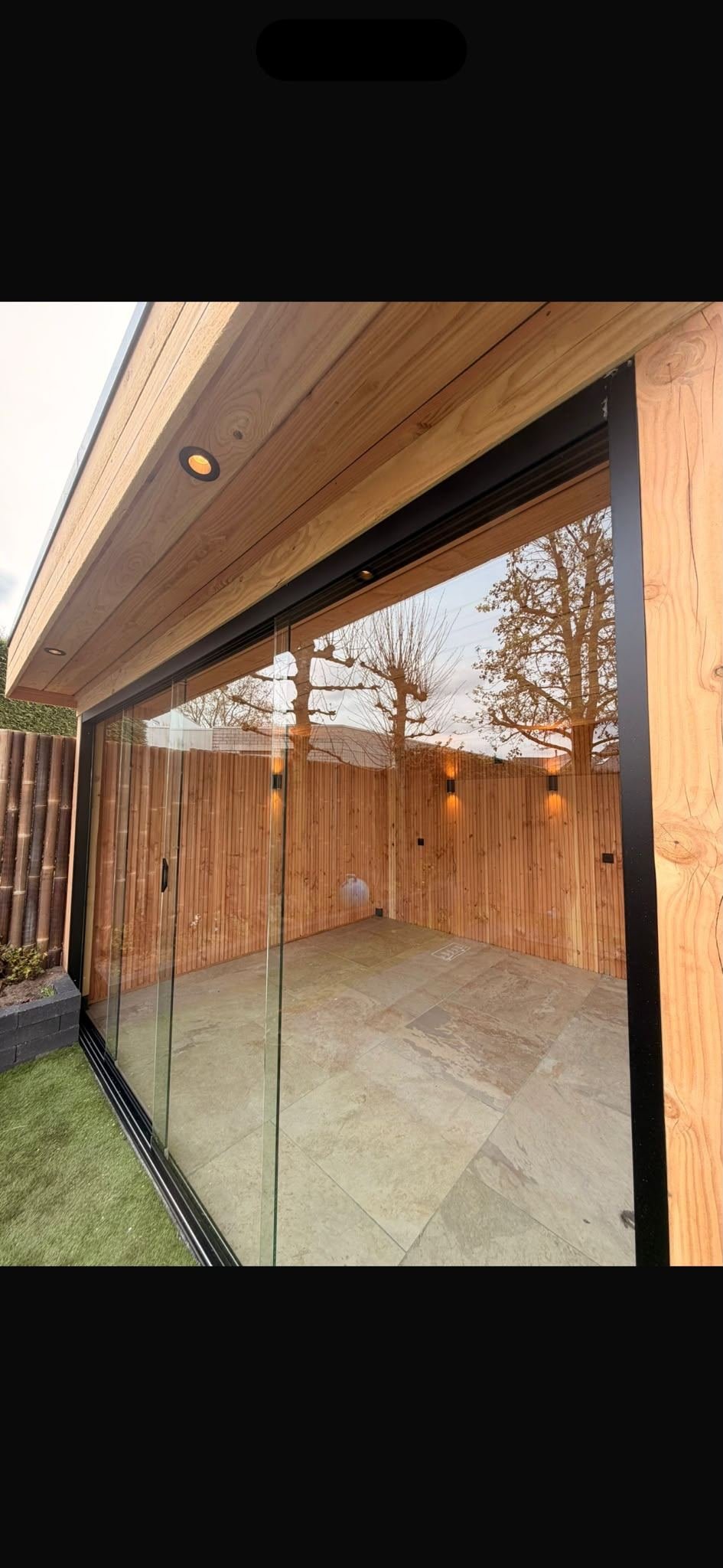 Overkapping met glazen schuifwand en inbouwspots in het houten plafond